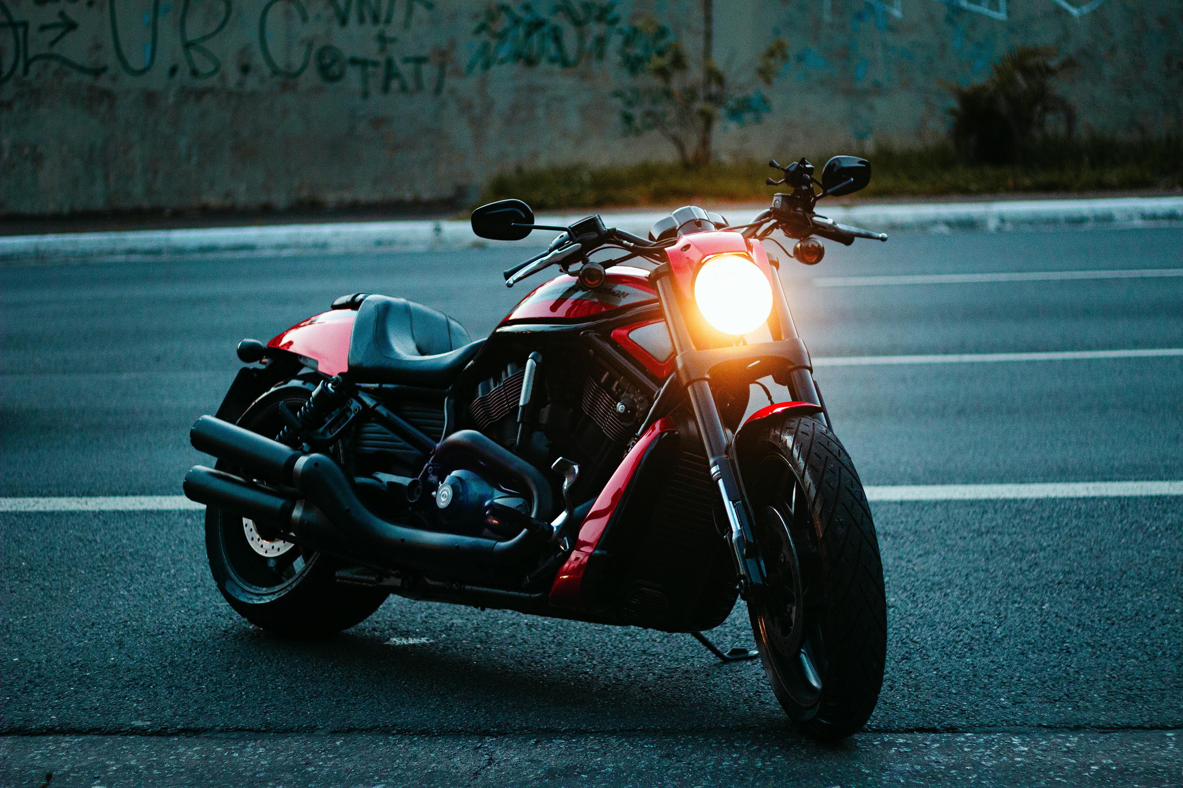 Modern motorcycle with headlight on, parked on urban street at night.