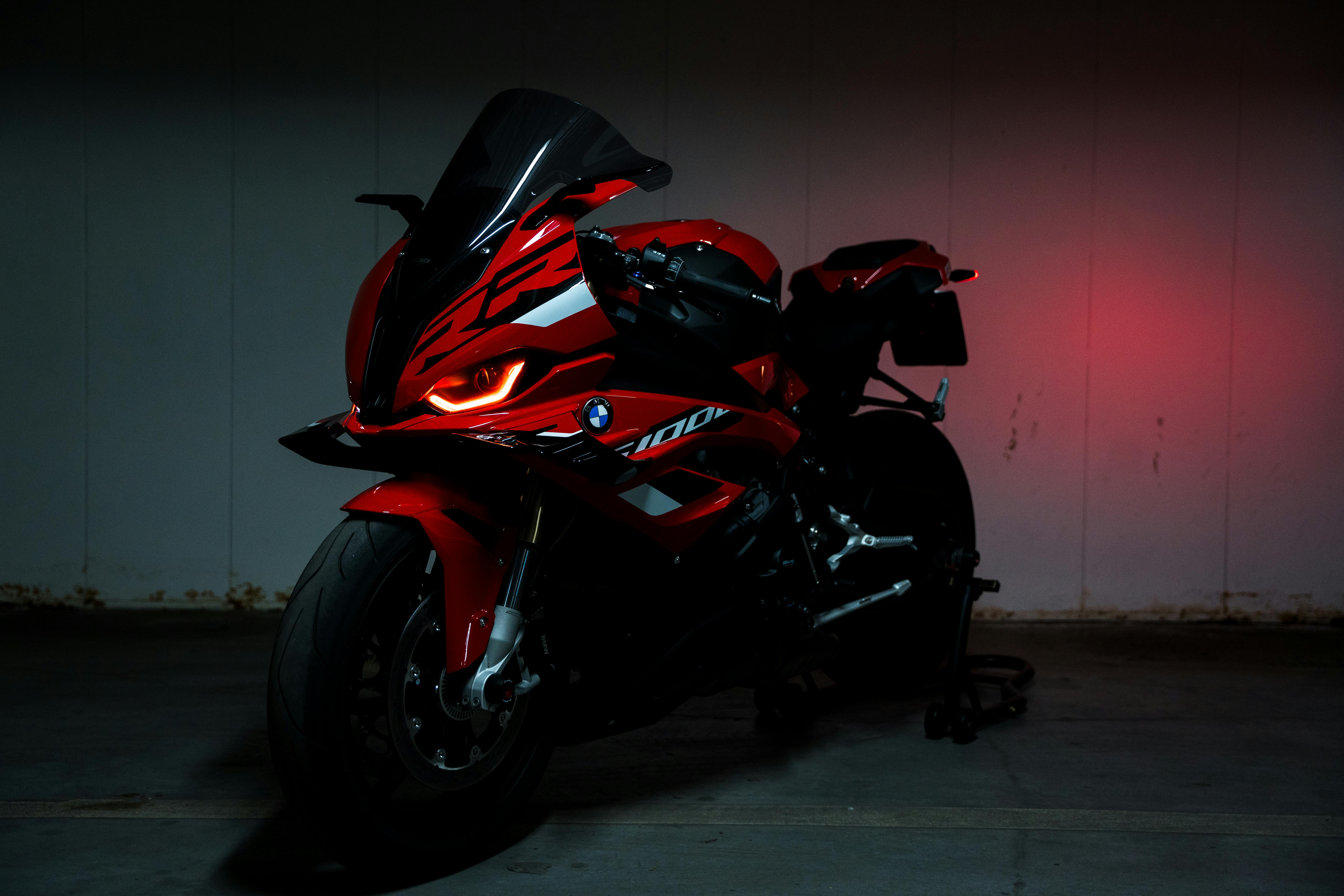 Bold red sports motorcycle parked indoors under dramatic lighting, showcasing sleek design and power.